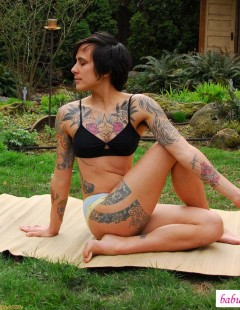 Разминка женщины с татуировками на природе